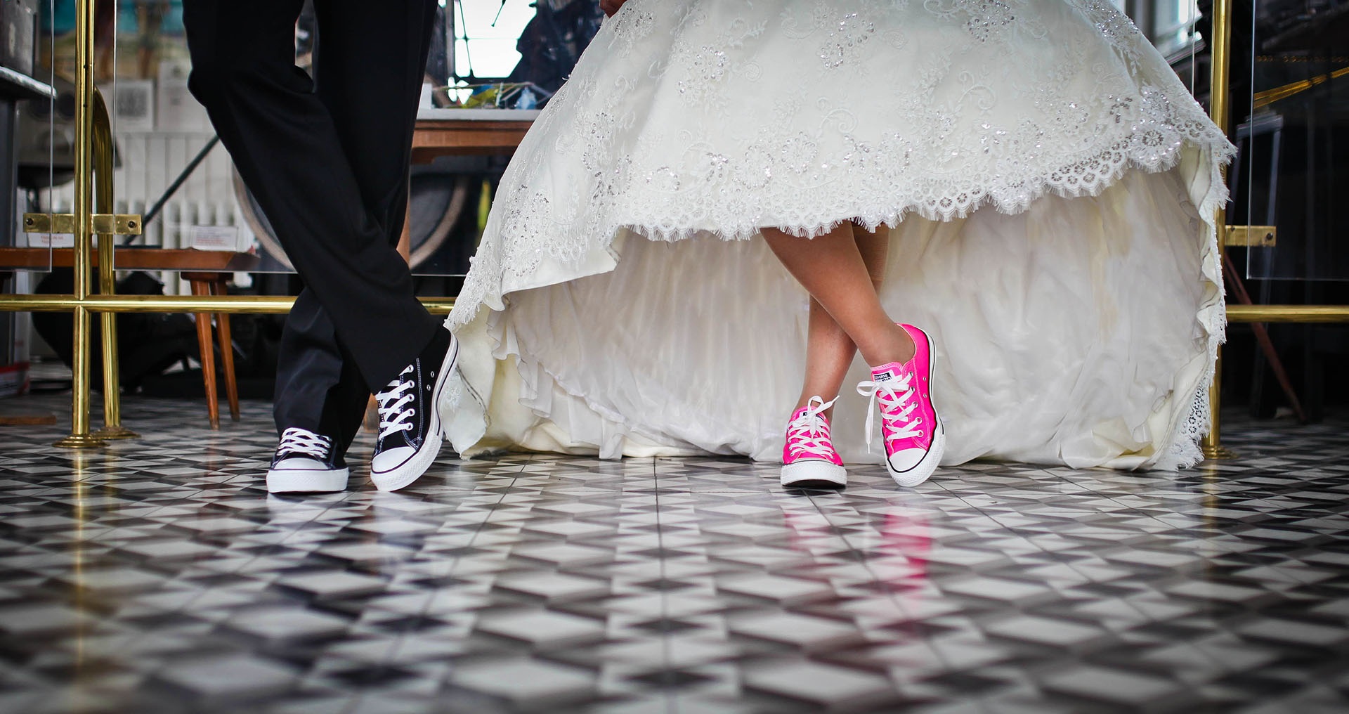 Foto das pernas do noivo com all star preto e vestido da noiva do joelho para baixo com all star rosa