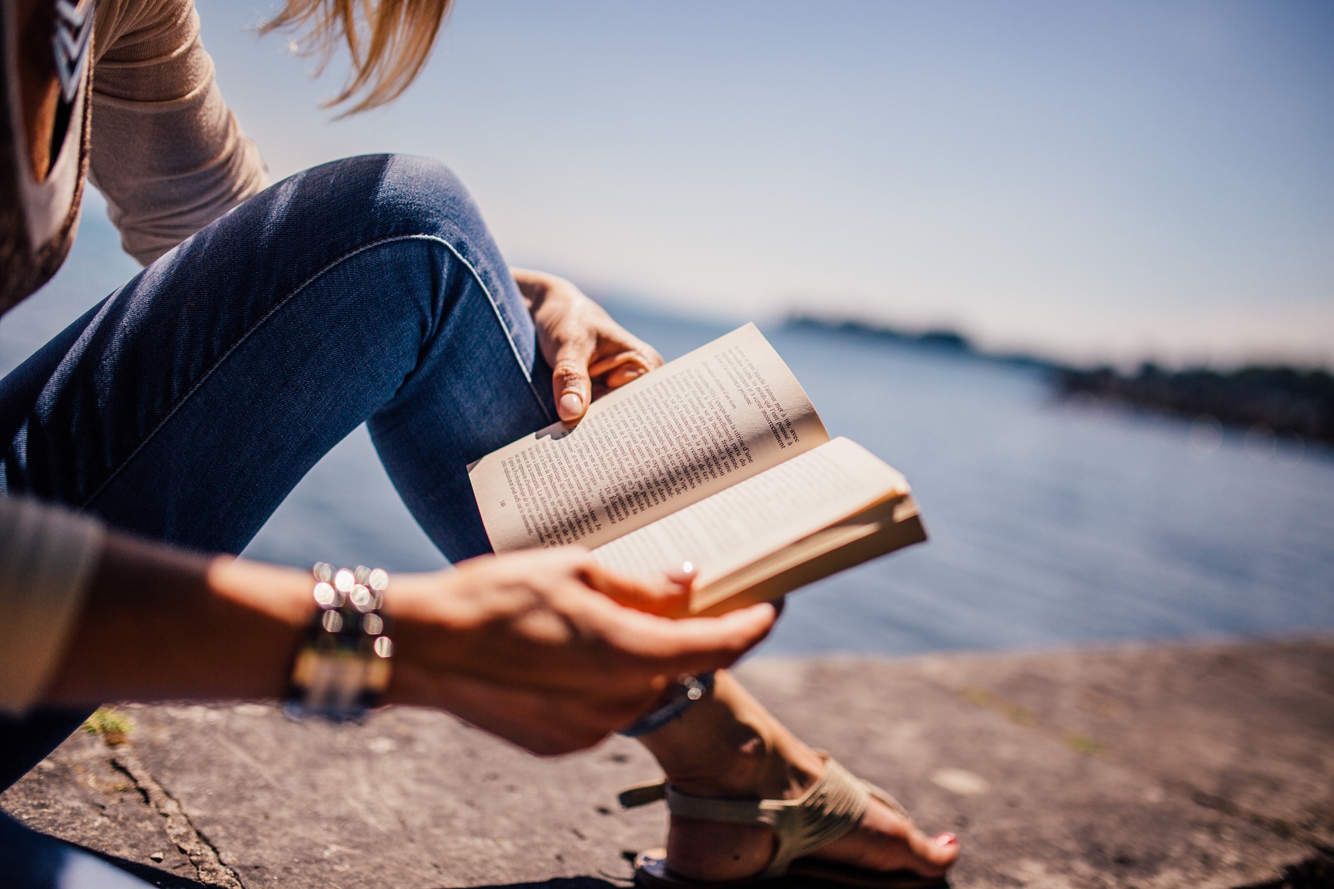 Garota sentada em uma pedra, lendo um livro