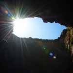 vista do sol e céu de dentro de uma caverna