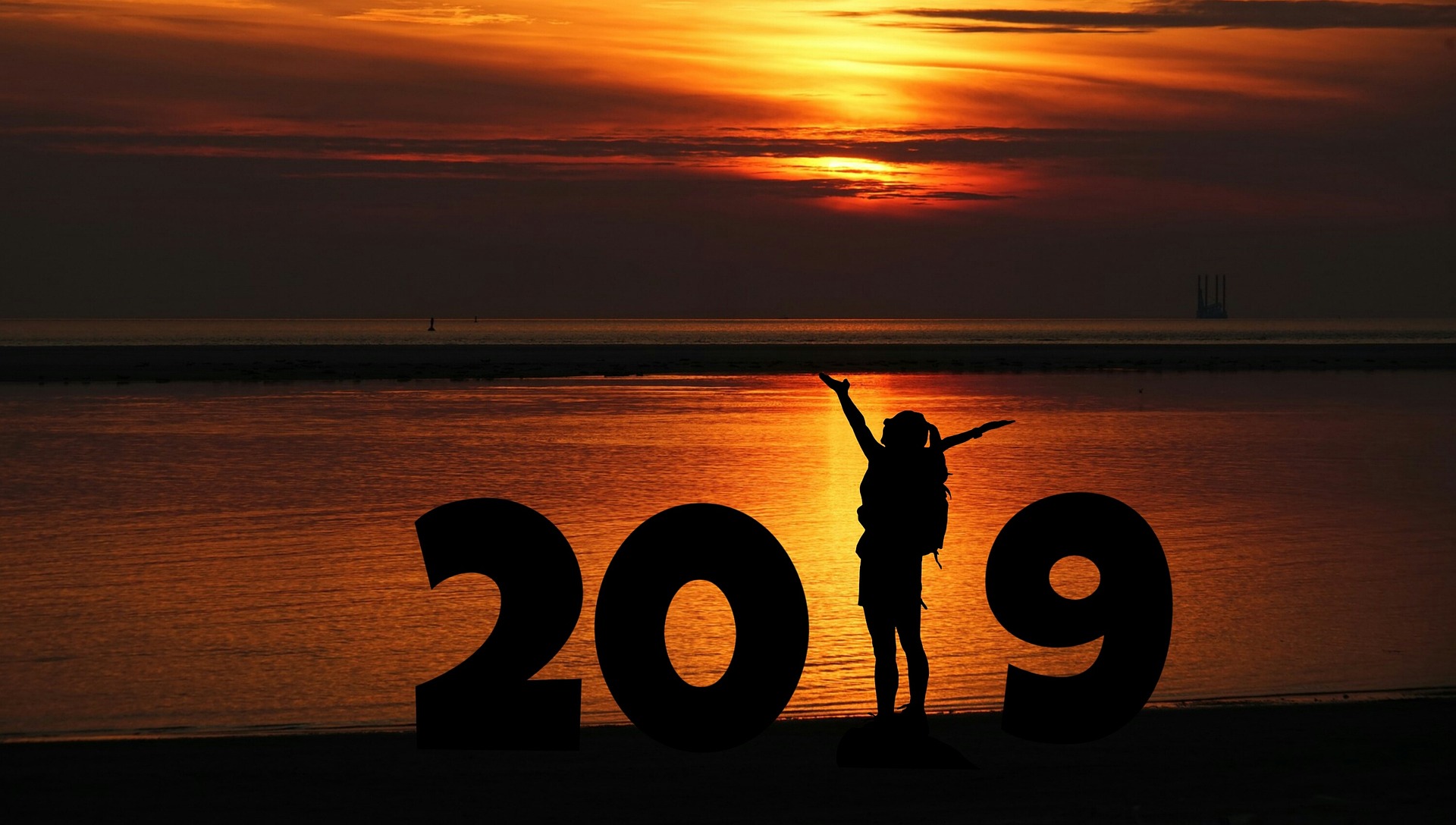 2019 formado por números e mulher de braços abertos representando o 1. Pôr do sol num lago ao fundo