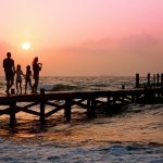 família andando em píer na praia